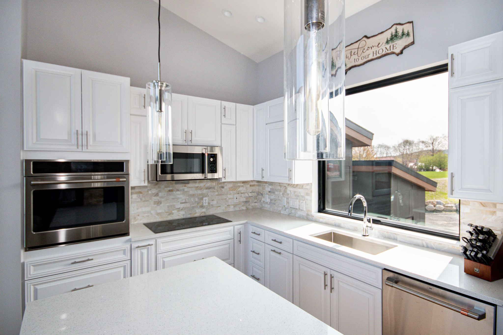 White kitchen with Classic Stoneworks backsplashes, lit by natural light from an open window.