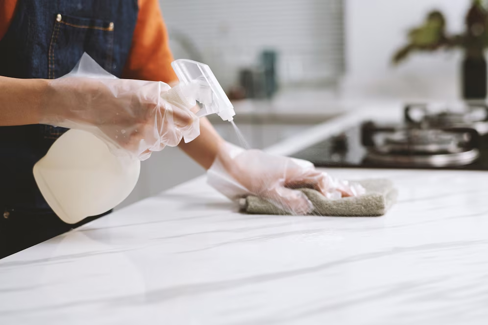 Woman cleaning a countertop, representing marble countertop maintenance.