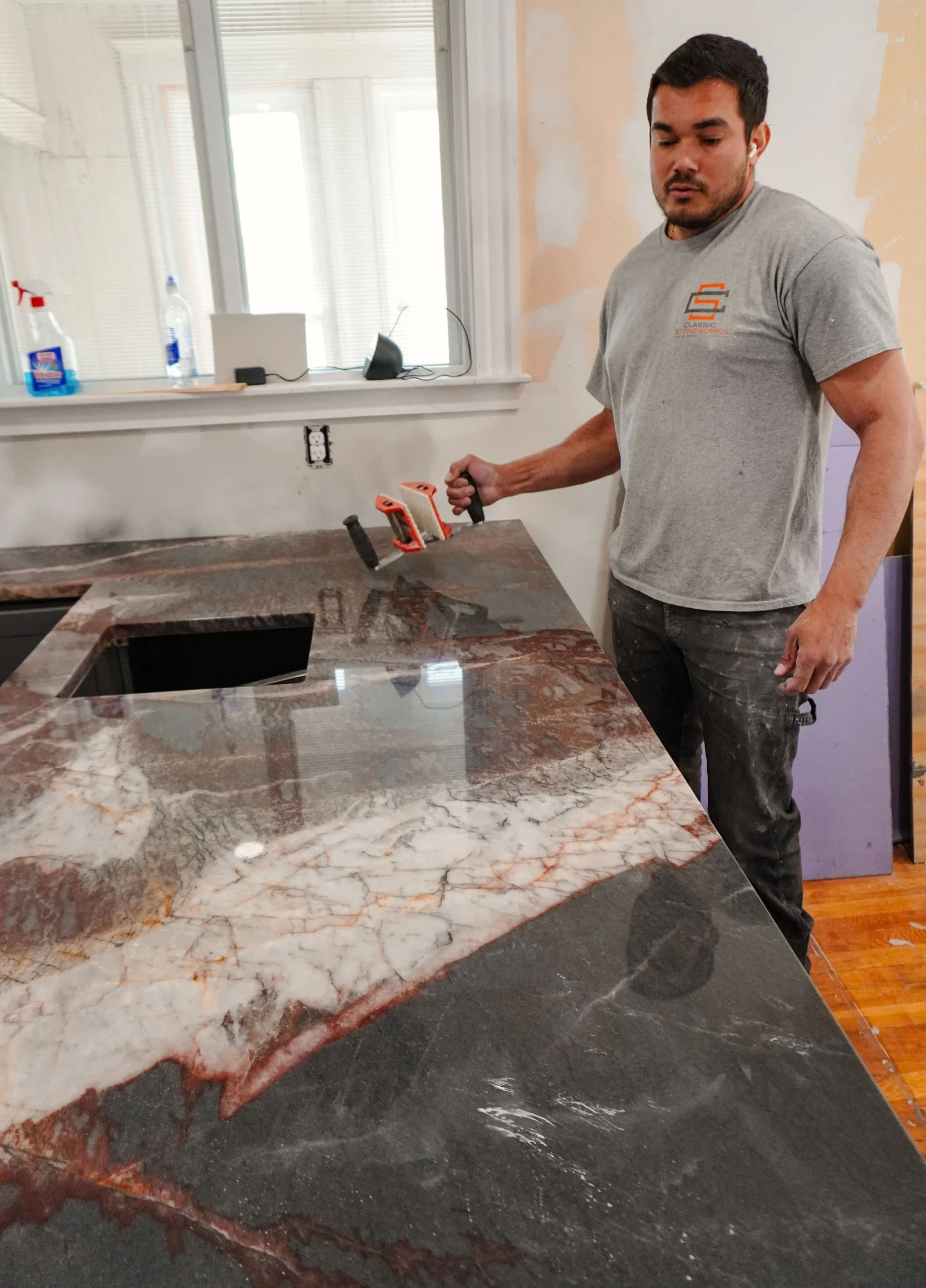Person cleaning granite countertop highlighting maintenance routine in a bright kitchen