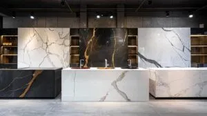 Realistic interior photography, elegant kitchen design studio showroom atmosphere, three large stone countertop slabs displayed side by side on a wide kitchen island, left slab showing dramatic black and gold granite with deep crystalline flecks, center slab featuring pristine white quartz with subtle grey veining, right slab revealing classic Calacatta marble with bold flowing veins, each surface partially polished and partially honed showing contrasting finish options, warm recessed lighting overhead accentuating the depth and texture of each material, a stone fabricator's diamond blade tool and measuring template resting nearby, photorealistic, high resolution, professional product and interior design photography